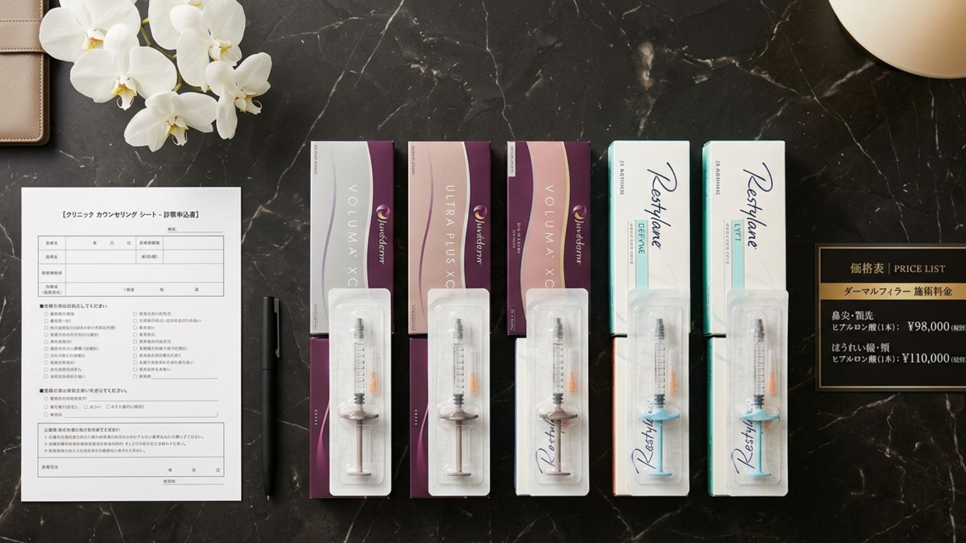 Dermal filler syringes arranged by treatment area on dark marble surface with Japanese clinic consultation form and pen